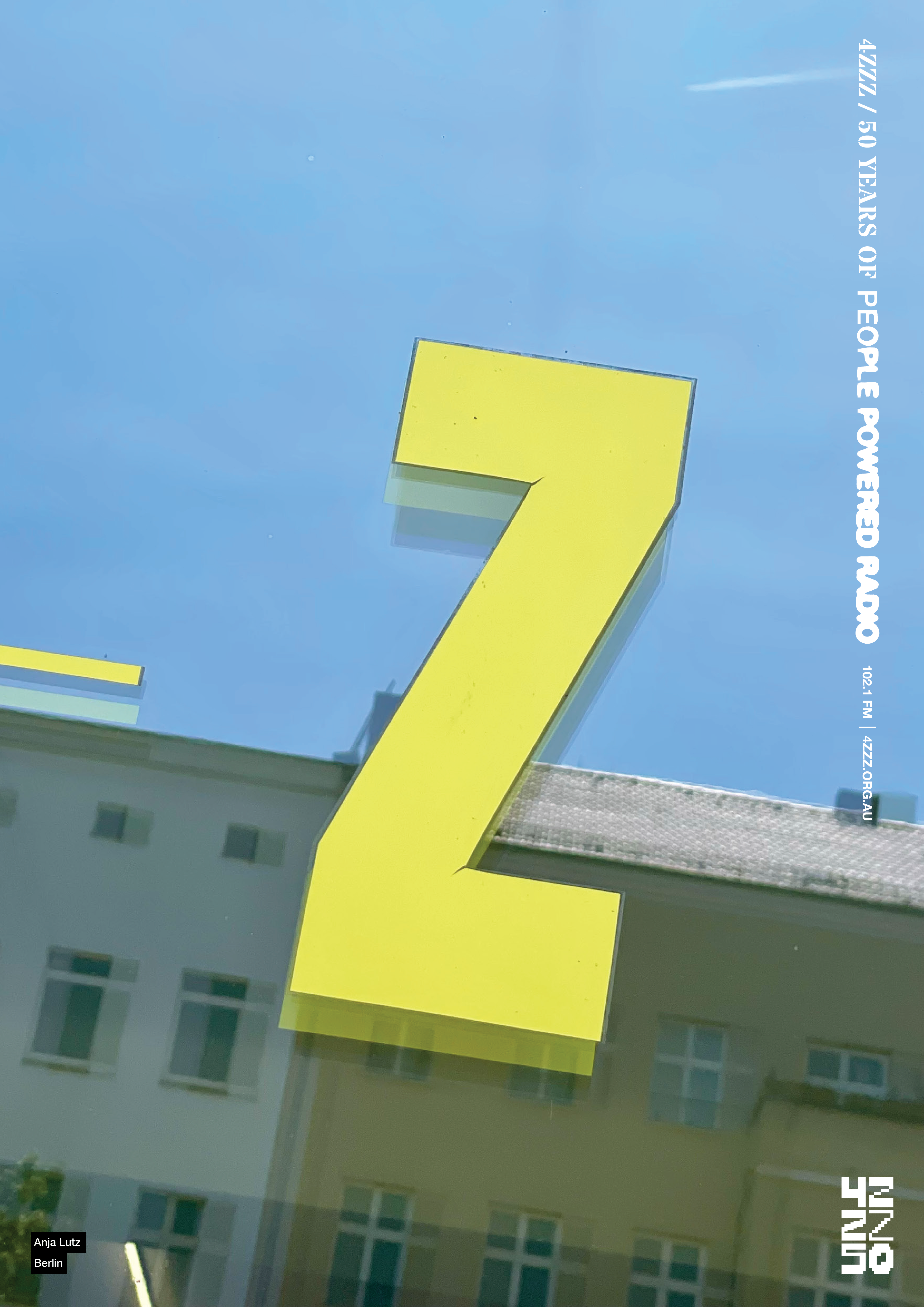 A Yellow Z sits on a reflective surface ,the sky and tops of buildings are captured in the reflection.