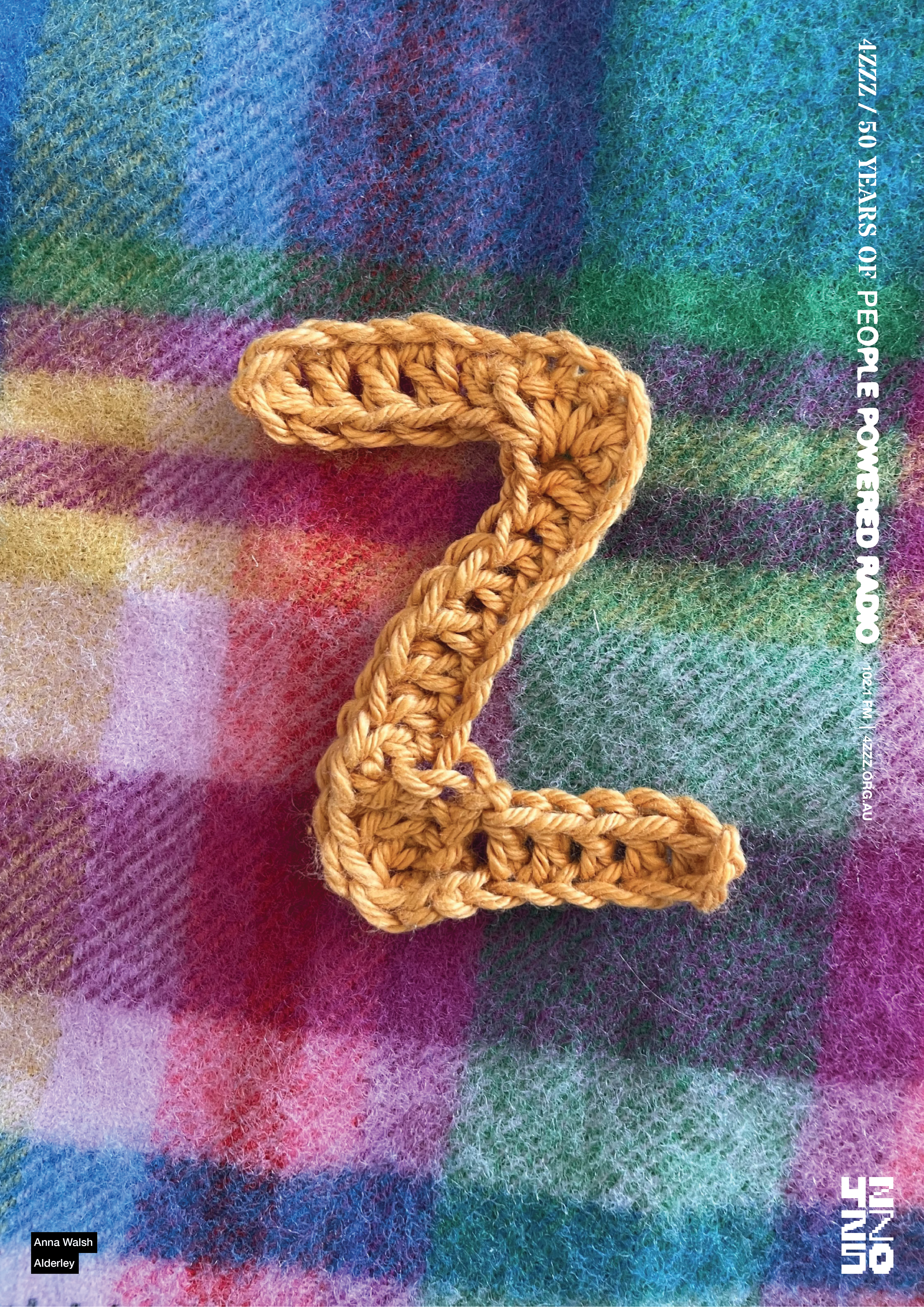 A yellow crochet Z sits on a blue and pink woven blanket.