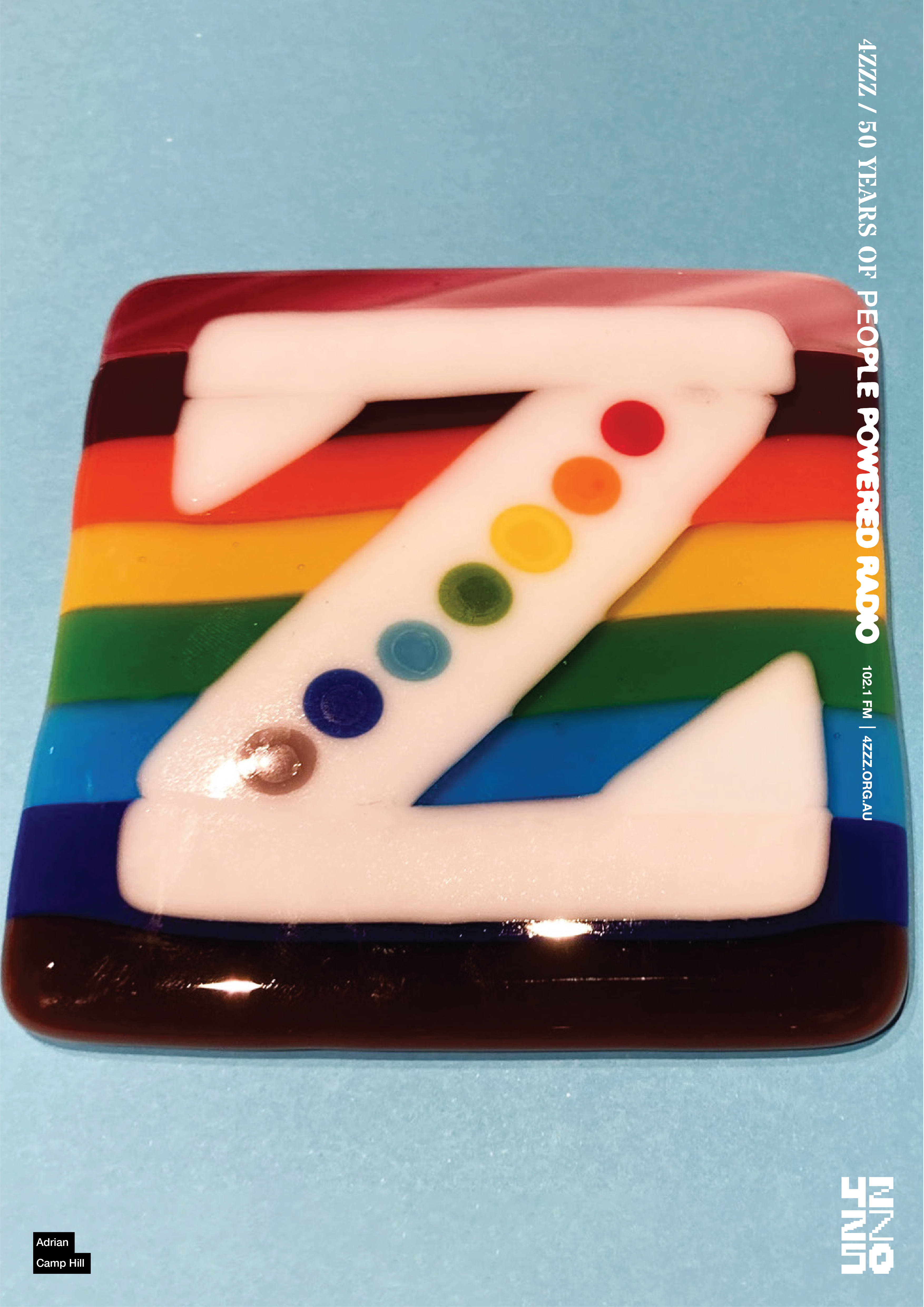a glass square on a light blue background. The square is made of rainbow horizontal stripes, with a Z in white inlaid the colourful layers. The diagonal stroke of the Z has a line of rainbow dots. 
