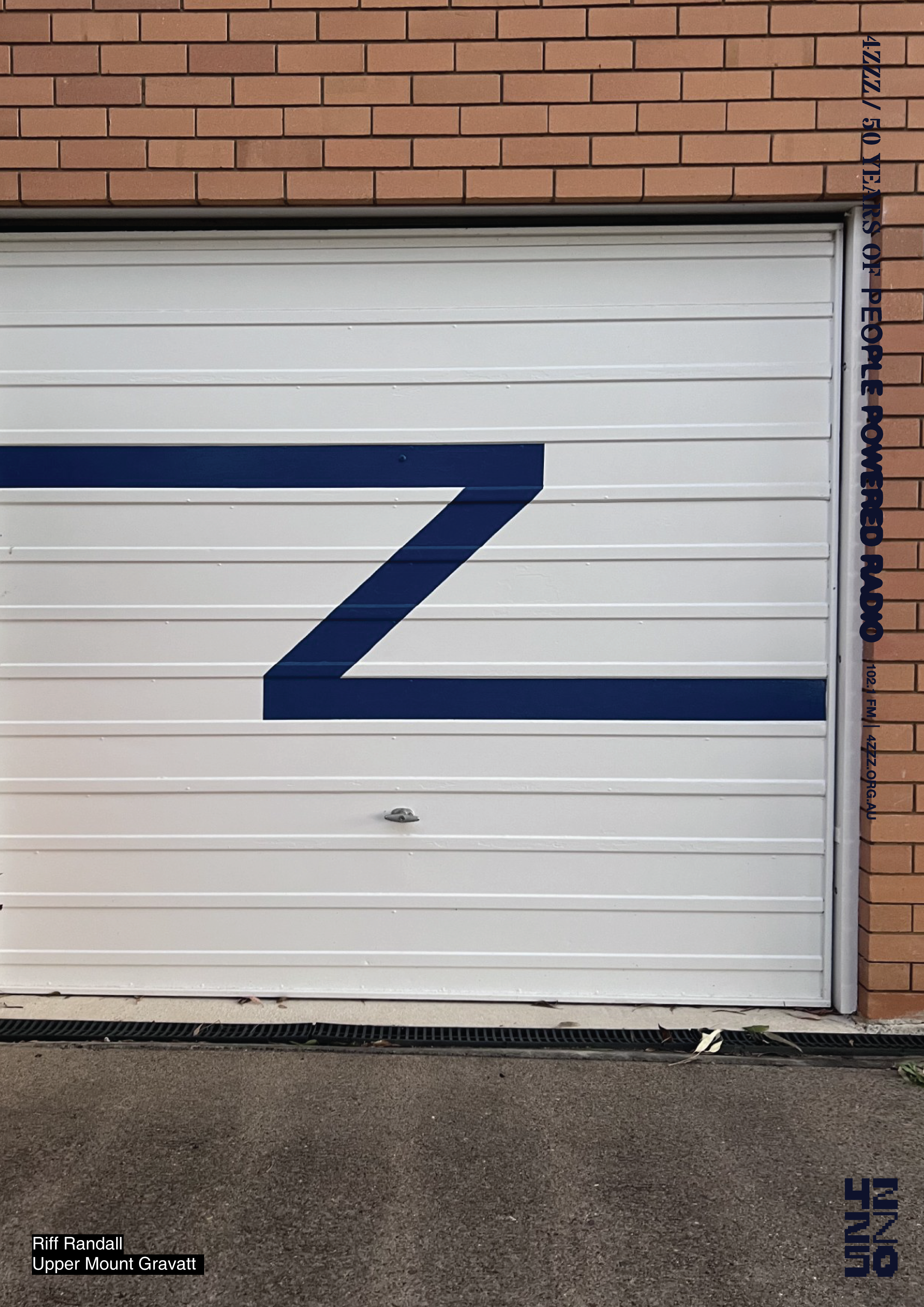 a photograph of a brick house with a white metal garage door, a navy blue