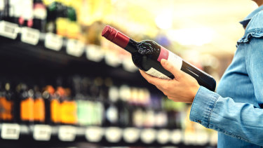 A person holding a bottle of wine in a shop.
