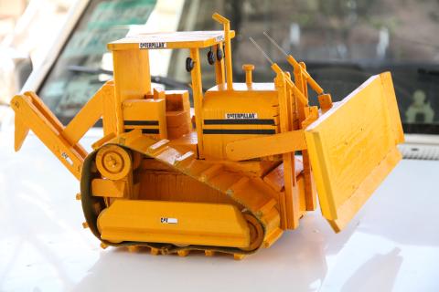 A small orange bulldozer placed on a white car.
