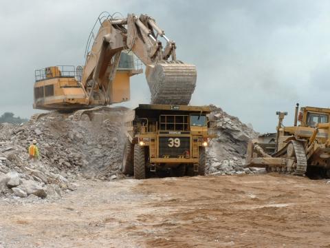 A mining location with a mining device looking over mounds of rubble.