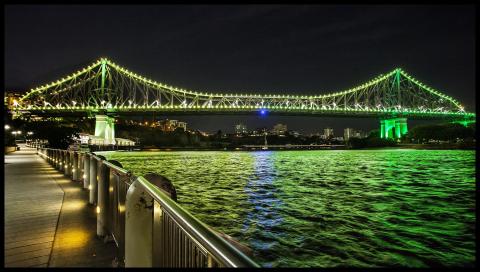 A view of the Story Bridge lit up at night from the Eagle Street Pier.