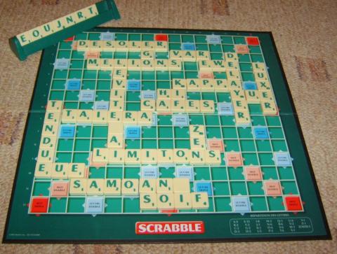A classic Scrabble board game in-play placed on carpet.