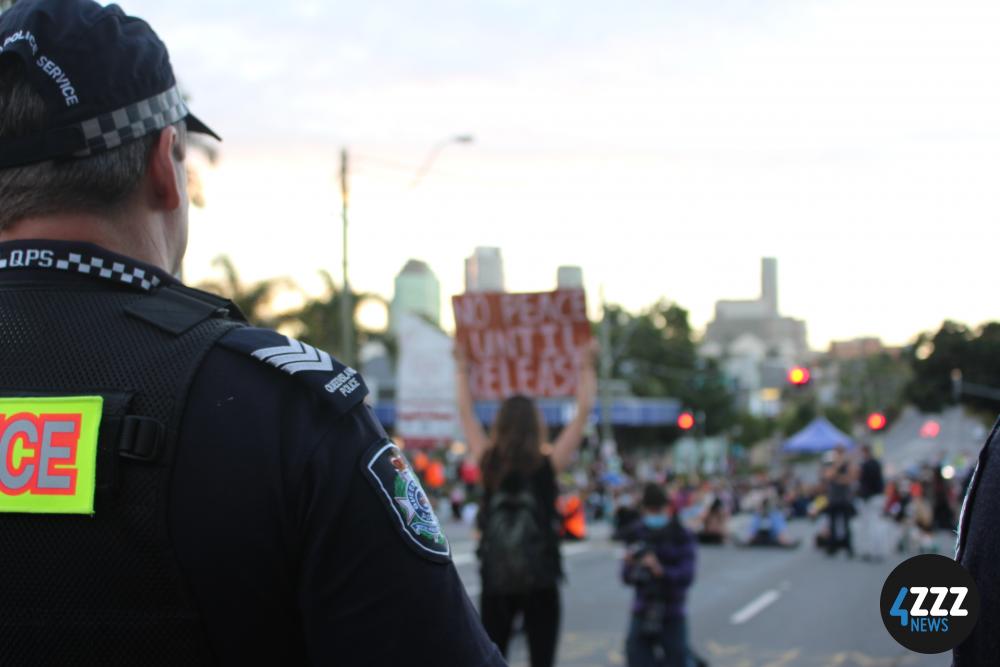 A front line of protesters faces a front line of police on Main St. [4ZZZ/Lillian Rangiah]