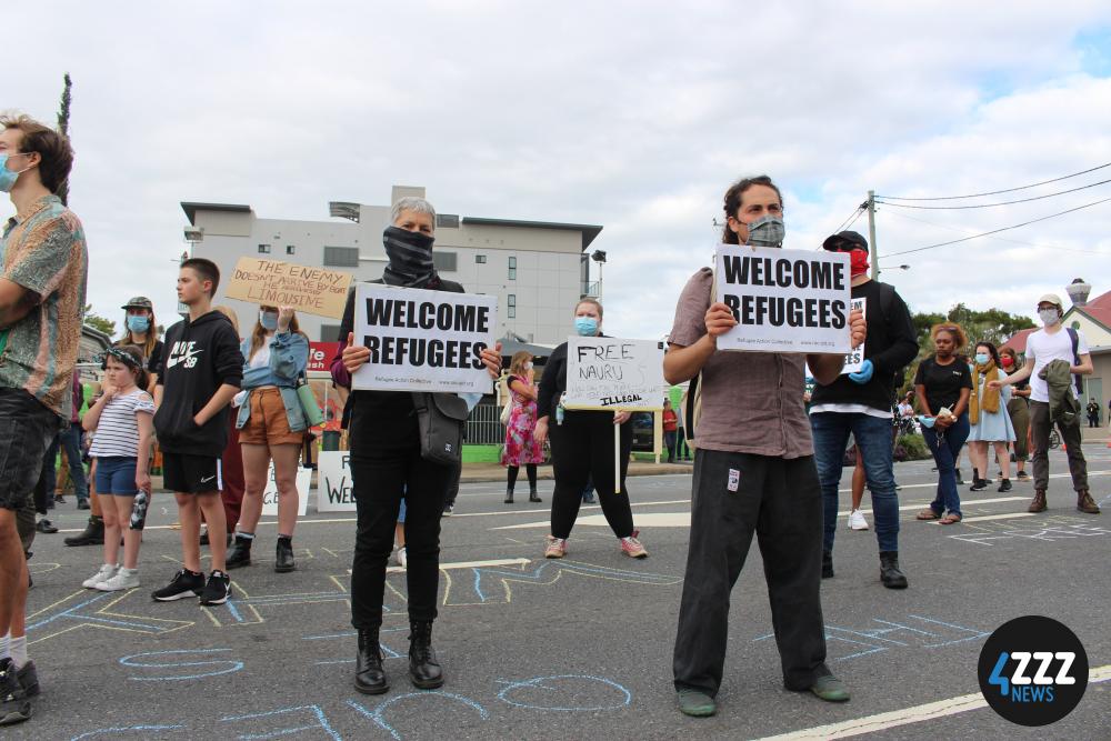 Protesters hold signs up for detainees to see from their balcony. [4ZZZ/Lillian Rangiah]