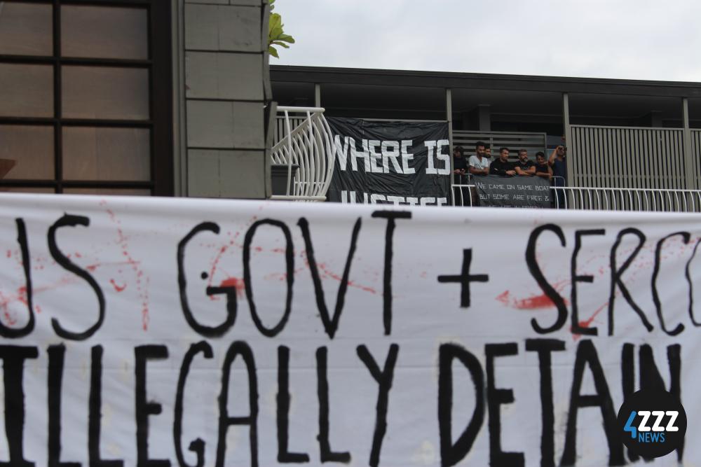 Protesting detainees look on from their balcony during speeches by activists on Main St. [4ZZZ/Lillian Rangiah]