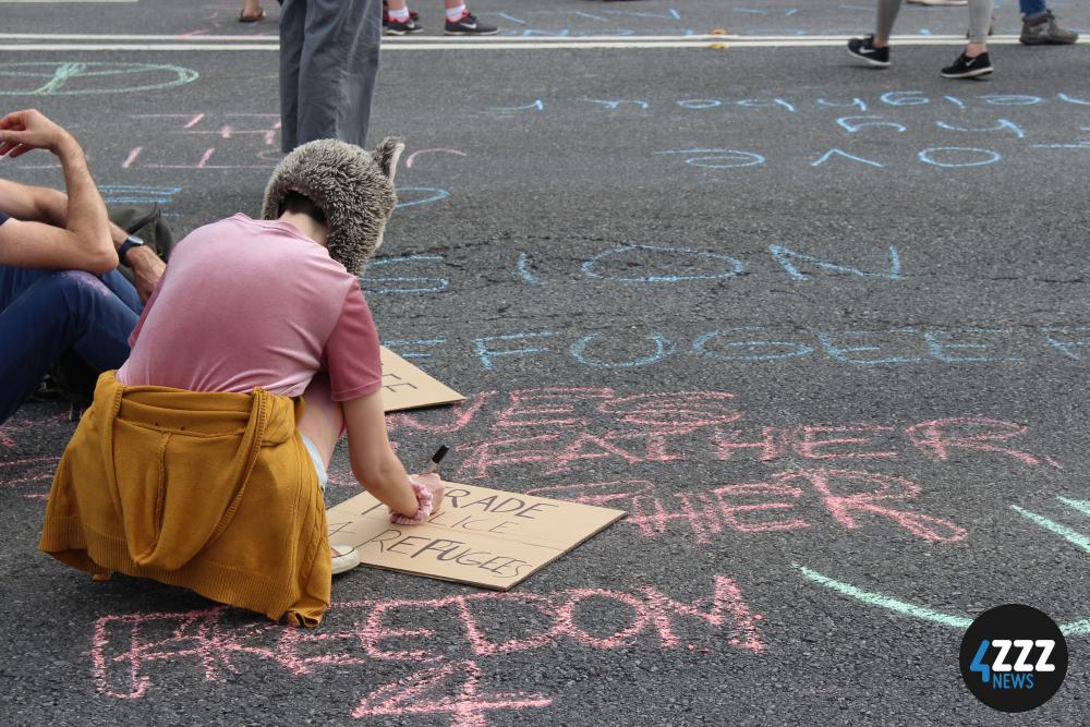 Some protesters improvise cardboard signs. [4ZZZ/Lillian Rangiah]