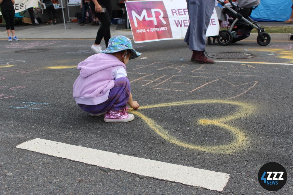 Several kids add their own artworks to the road. [4ZZZ/Lillian Rangiah]