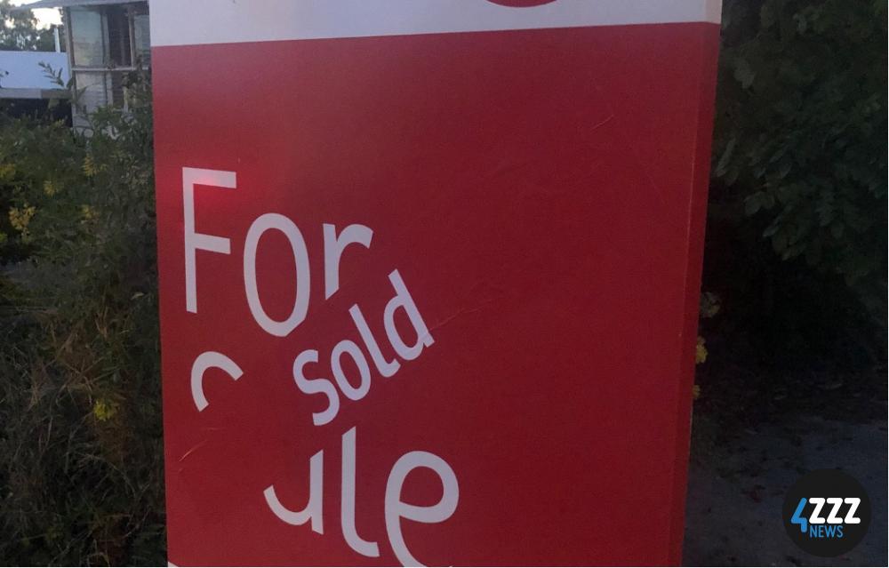 A red for sale sign with a sold sticker placed over it