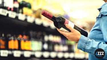 A person holding a bottle of wine in a shop.